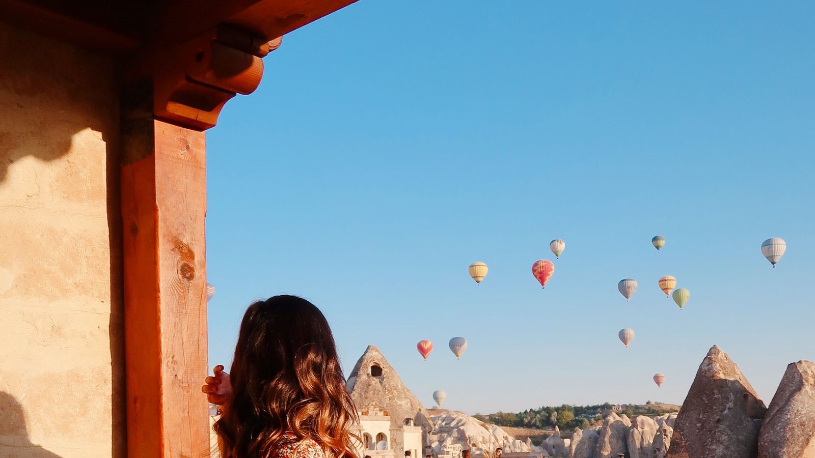 A guest watching the balloons from a cave-hotel terrace