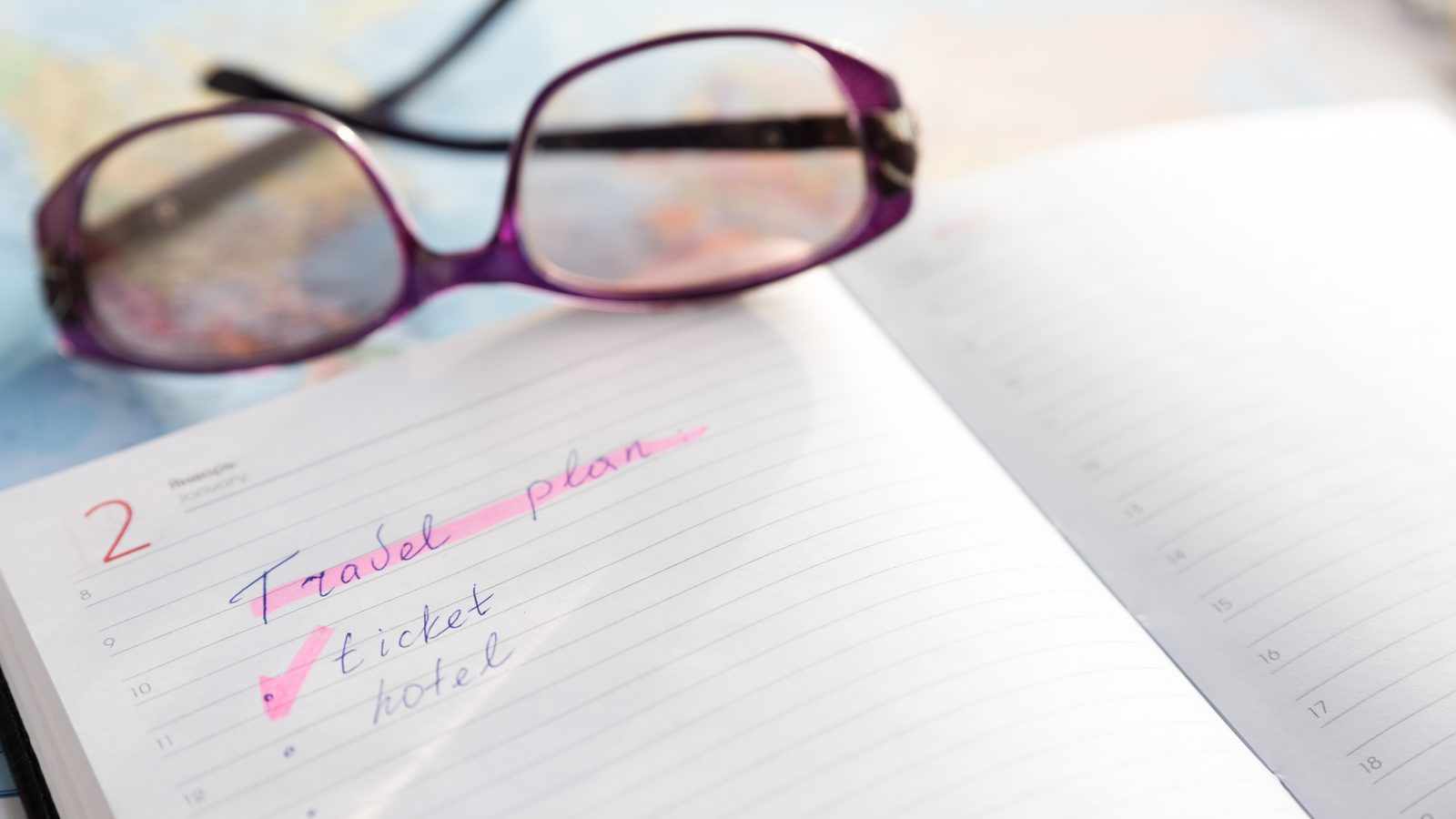 Reading glasses resting on an open travel planner