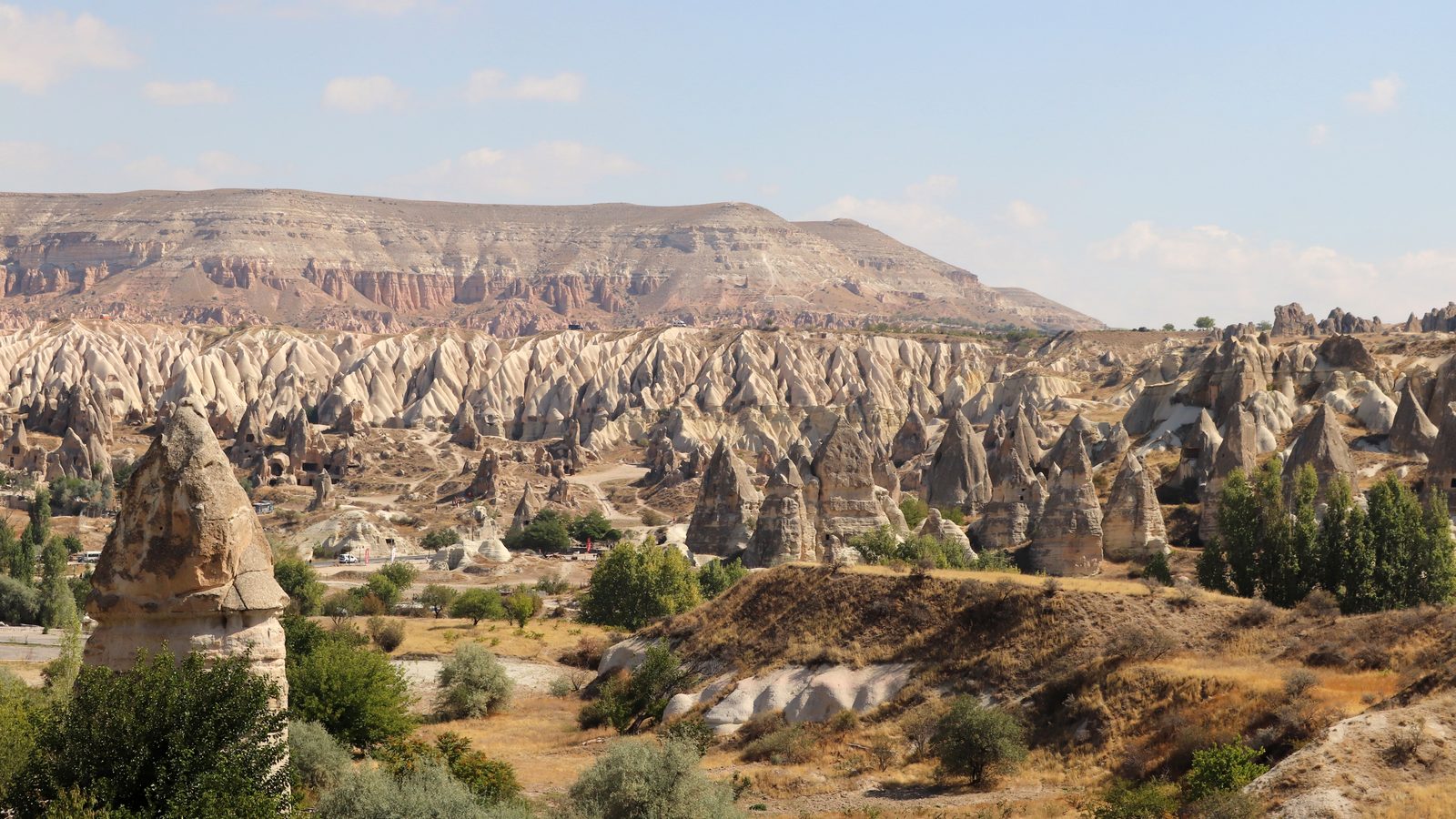 Fairy chimneys below the tuff escarpment near Göreme, dry and pale in late-season light